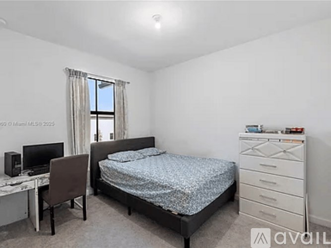 A bedroom with a bed, desk, and chair.