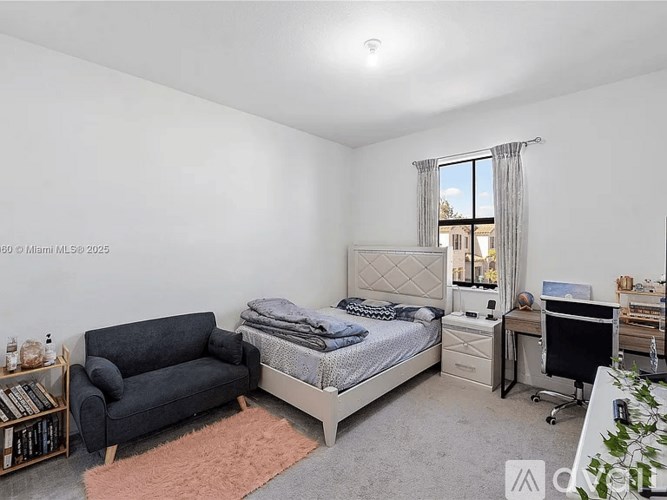 A bedroom with a bed, desk, and couch.