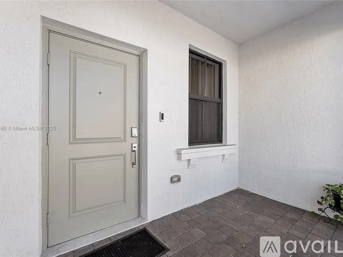 A room with a grey door and a window with a white wall.