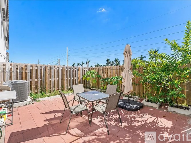 A patio with a table and chairs is surrounded by a wooden fence.