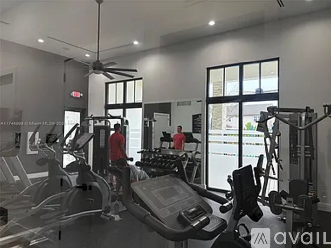 A gym with people working out and a fan in the background.