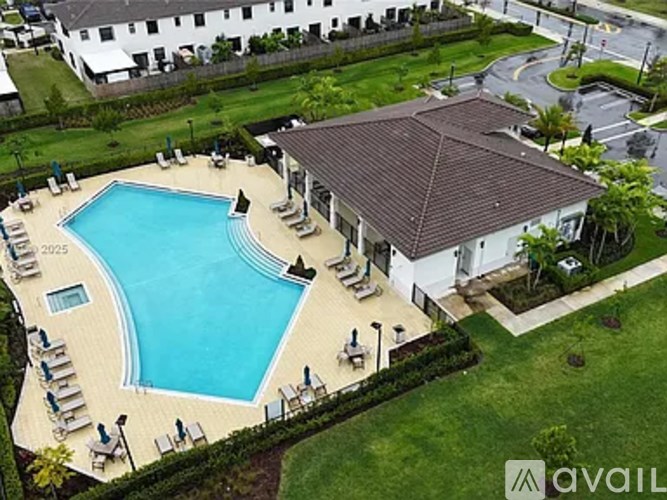A large swimming pool surrounded by lounge chairs and a building with a brown roof.