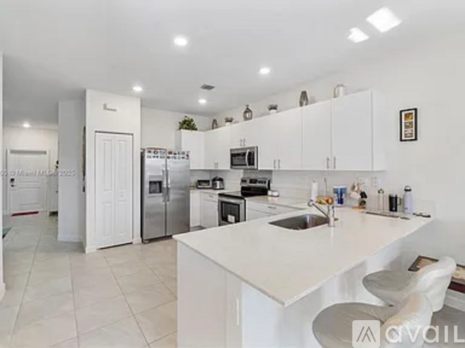 A white kitchen with a sink and a refrigerator.