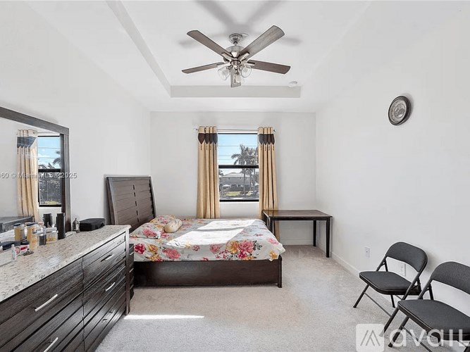 A bedroom with a bed, dresser, and window.