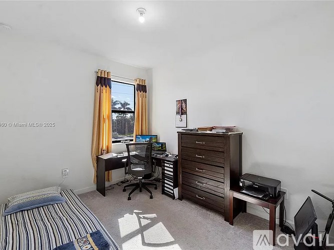 A bedroom with a bed, desk, and chair.