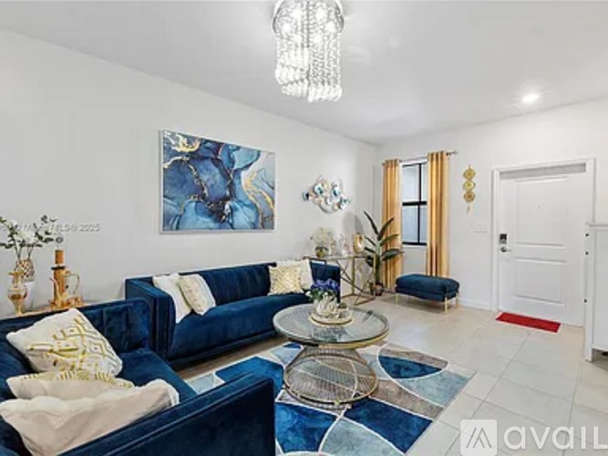 A living room with a blue couch and a chandelier.