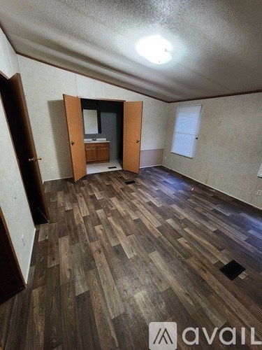 A room with wooden flooring and a bed in the corner.