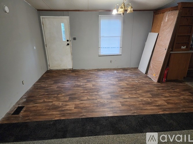 A room with wooden flooring and a door on the left side.