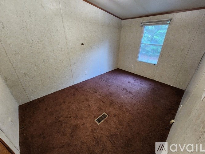 A room with a window and a brown floor.