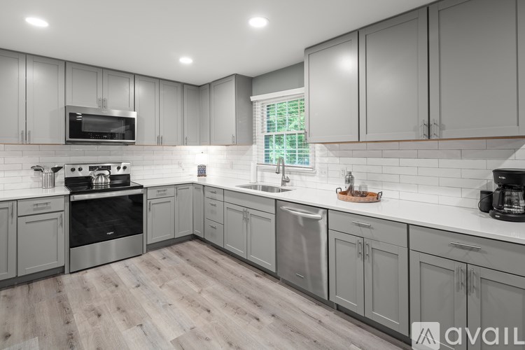 A modern kitchen with wooden floors and grey cabinets.