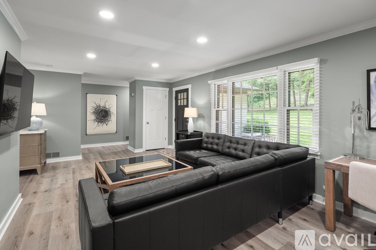A modern living room with a black leather sofa and wooden coffee table.