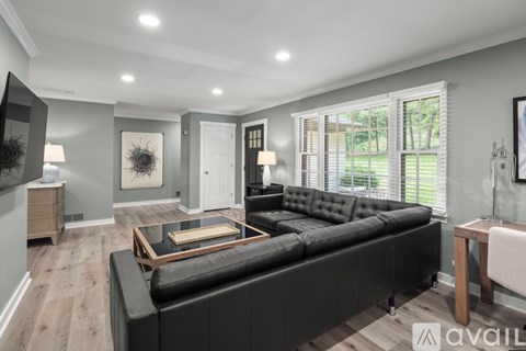A modern living room with a black leather sofa and wooden coffee table.