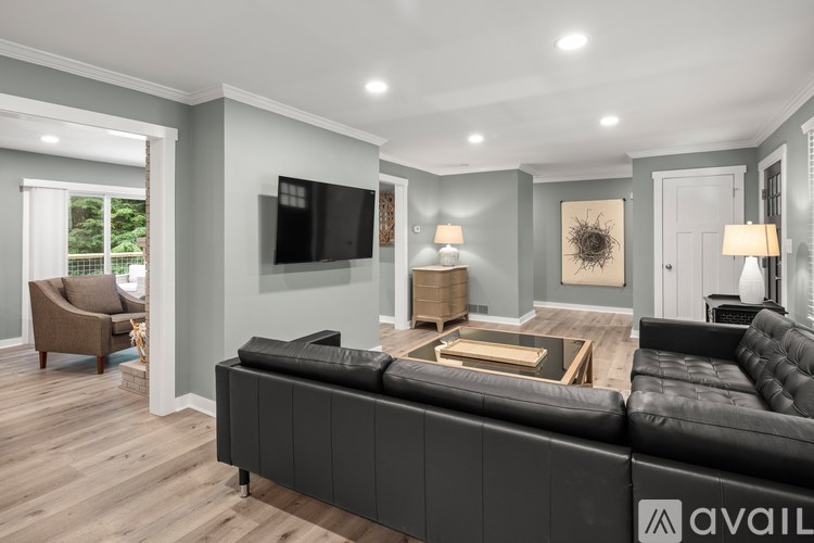 A modern living room with a black leather sofa and a television mounted on the wall.