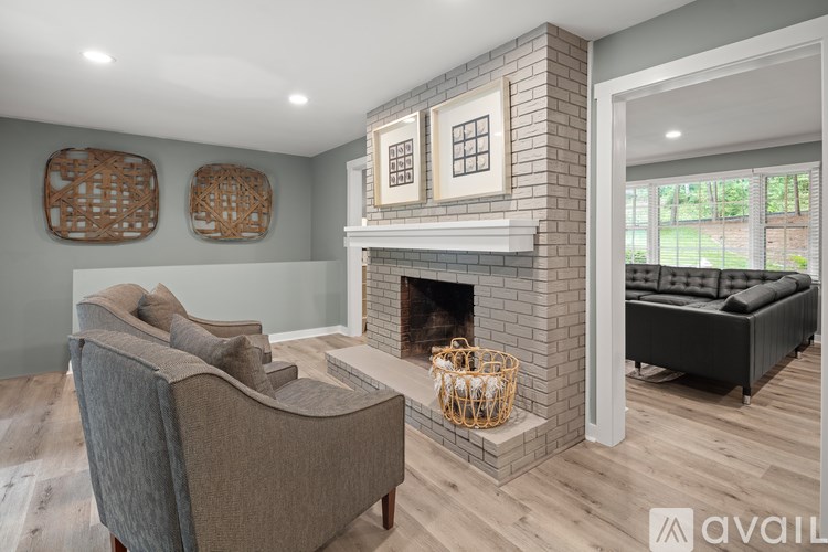 A living room with a grey sofa, a grey armchair, a fireplace, and a wooden floor.