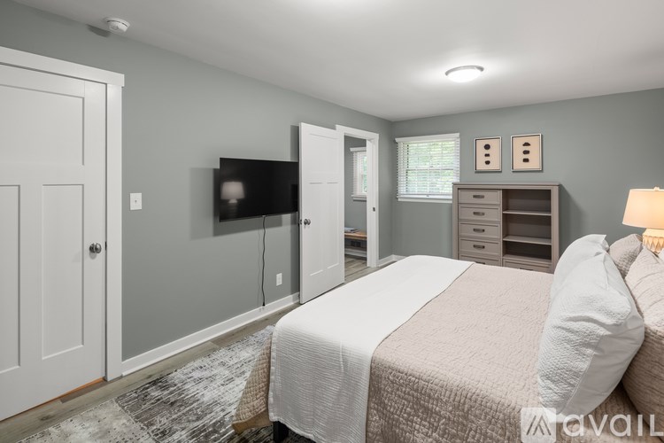 A bedroom with a bed, dresser, and a television.