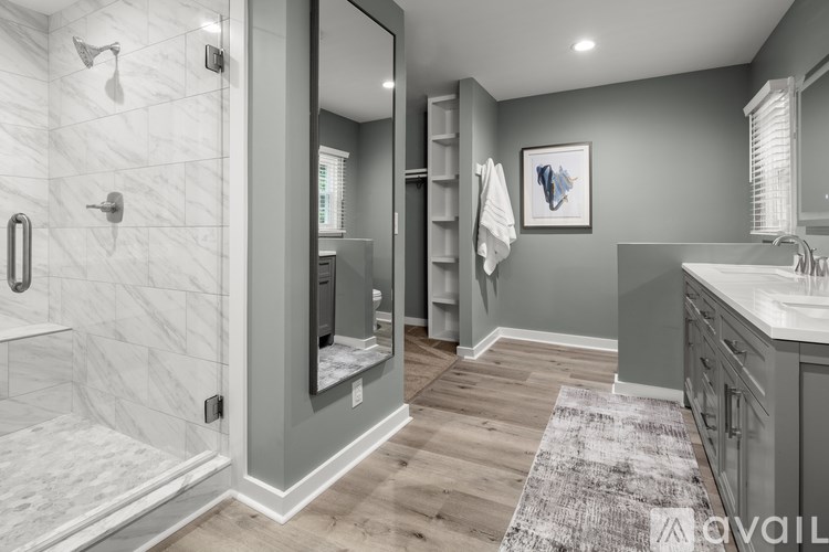 A bathroom with a marble shower and a wooden floor.