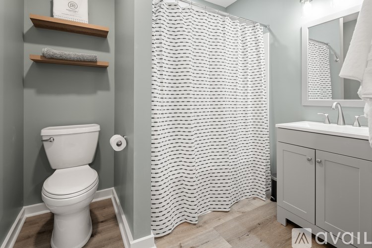 A white toilet sits next to a shower curtain in a bathroom.