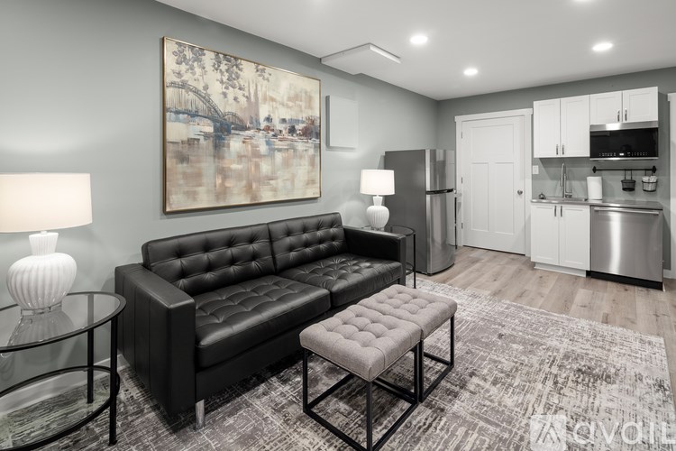 A black leather sofa with a glass table in front of it and a painting on the wall.