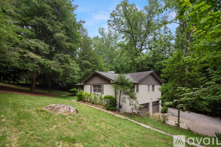 A house surrounded by greenery with a grassy lawn in front.
