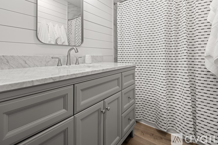 A bathroom with a white sink and grey cabinets.