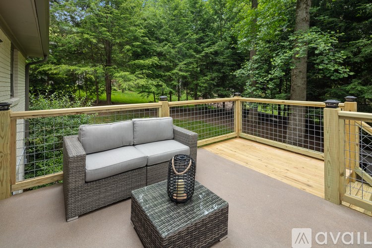A patio with a grey couch and a wicker table.