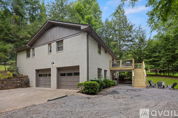 A house with a garage and a balcony is surrounded by greenery.