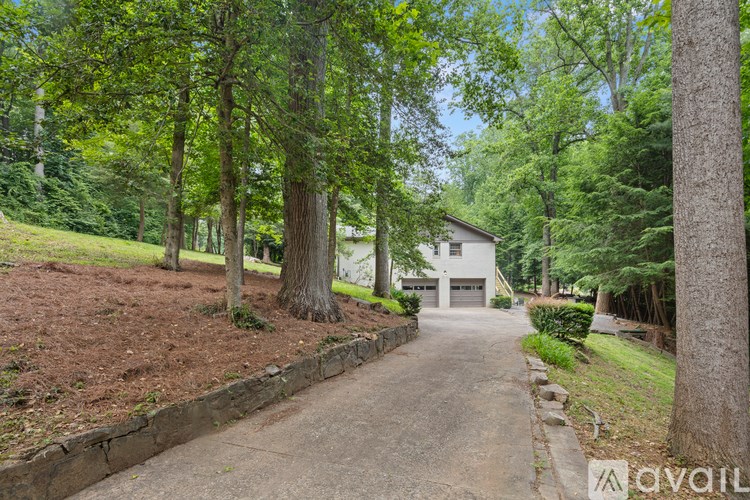 A house is surrounded by trees and a driveway leads to the front door.