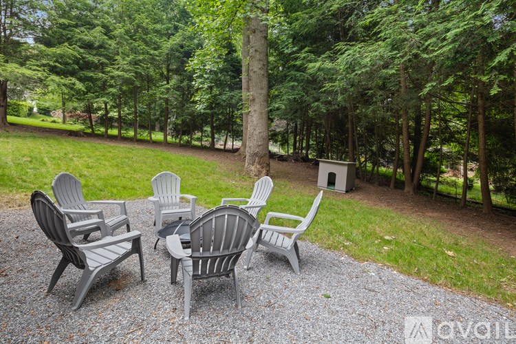 A set of chairs and a table are arranged on a gravel area in a backyard.
