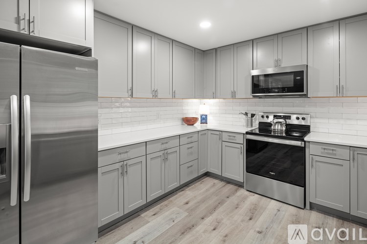 A modern kitchen with stainless steel appliances and wooden flooring.