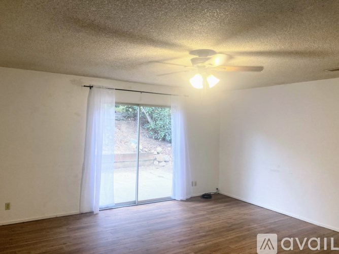 A room with a ceiling fan and sliding glass doors leading to a backyard.