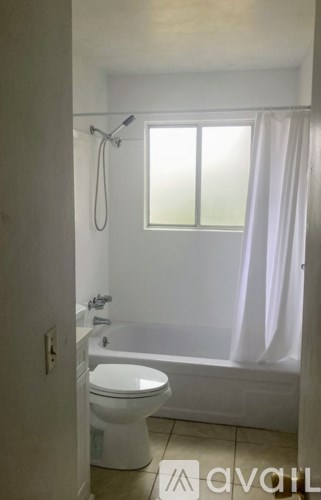 A white toilet is in a bathroom with a tub and shower.