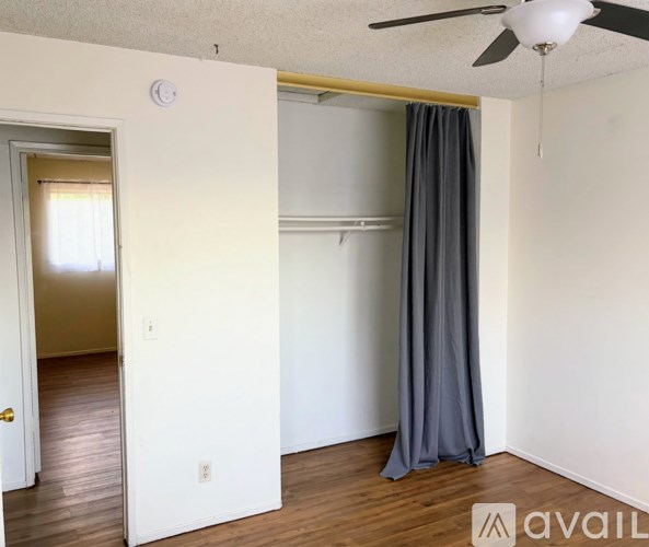 A room with a ceiling fan and a grey curtain.