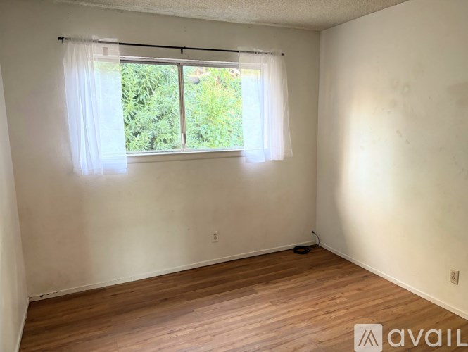 A room with a window and wooden flooring is available for rent.