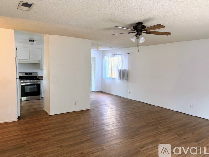 A spacious room with wooden floors and a ceiling fan.
