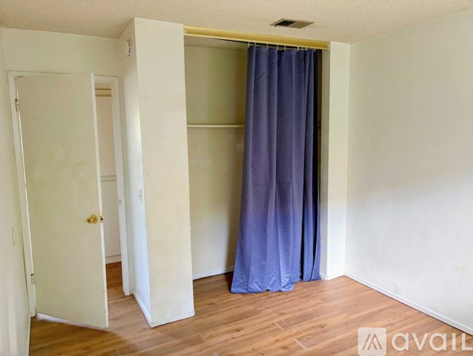 A room with a blue curtain and wooden floors.