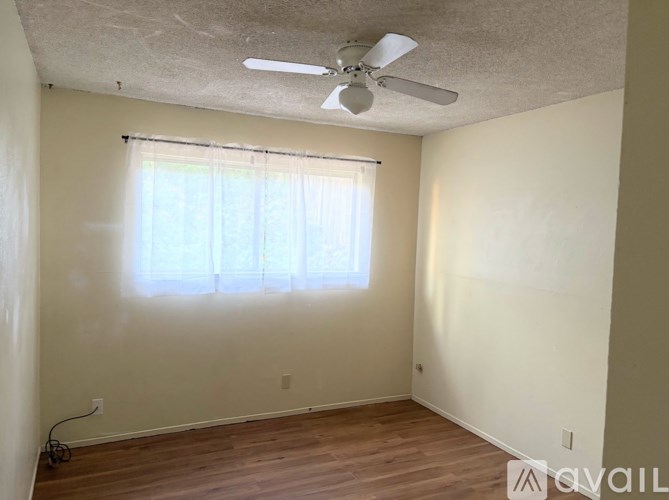 A room with a ceiling fan and a window with blinds.