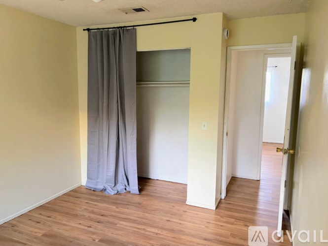 A room with a grey curtain and wooden floor.