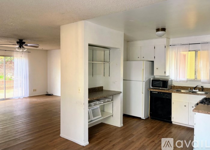 A kitchen with white appliances and wooden floors.