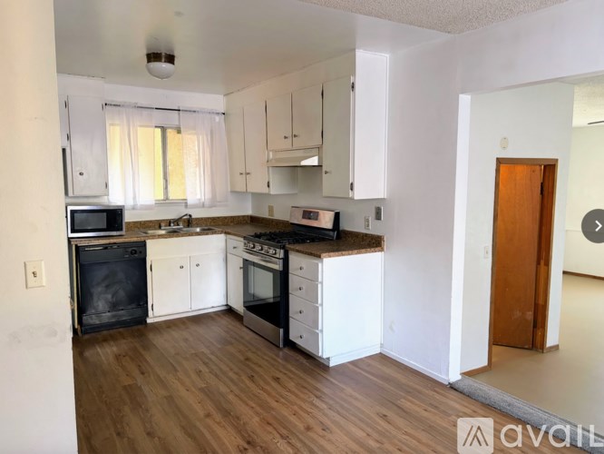 A kitchen with white cabinets and a wooden floor.
