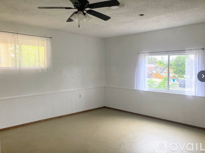 A room with a ceiling fan and two windows.