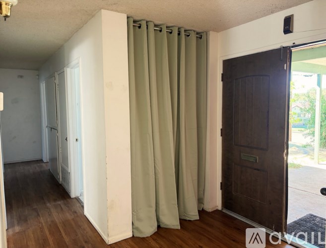 A room with a brown door and a green curtain.