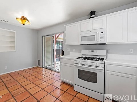 A kitchen with white cabinets and a tiled floor.
