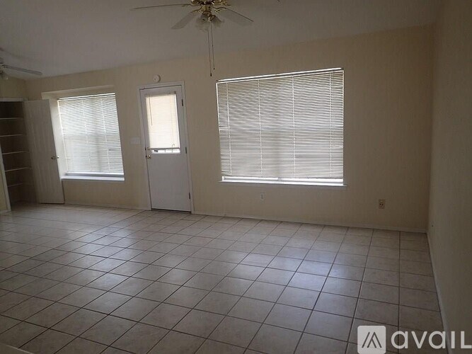 A room with a fan, two windows, and a tiled floor.