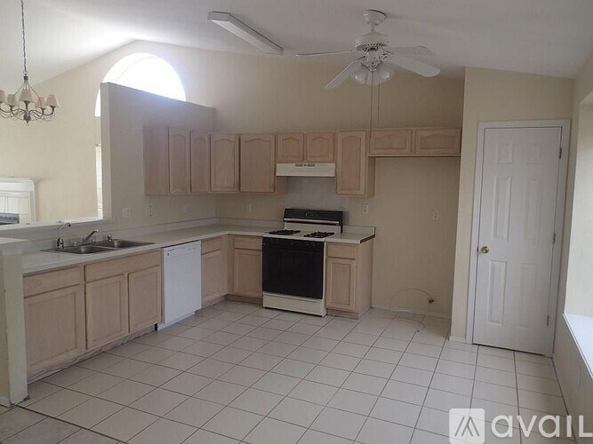 A kitchen with a white tile floor and a ceiling fan.