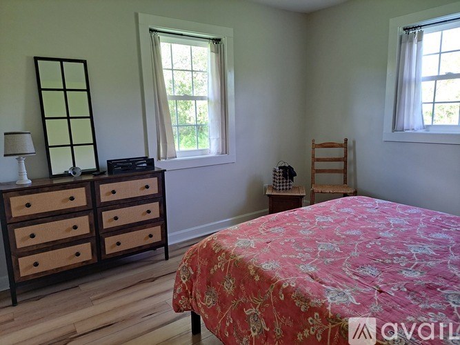 A bedroom with a bed, dresser, and window.