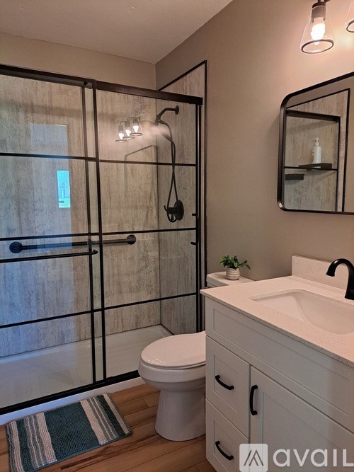A bathroom with a toilet, sink, and a glass shower door.