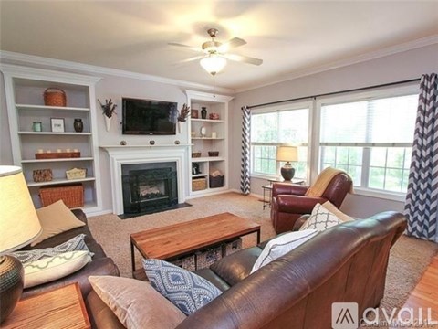 A living room with a fireplace and a television on the wall.