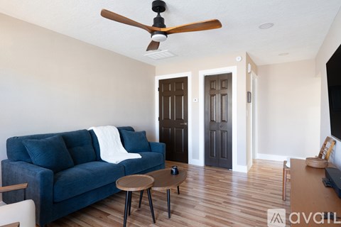 A living room with a blue couch and a ceiling fan.