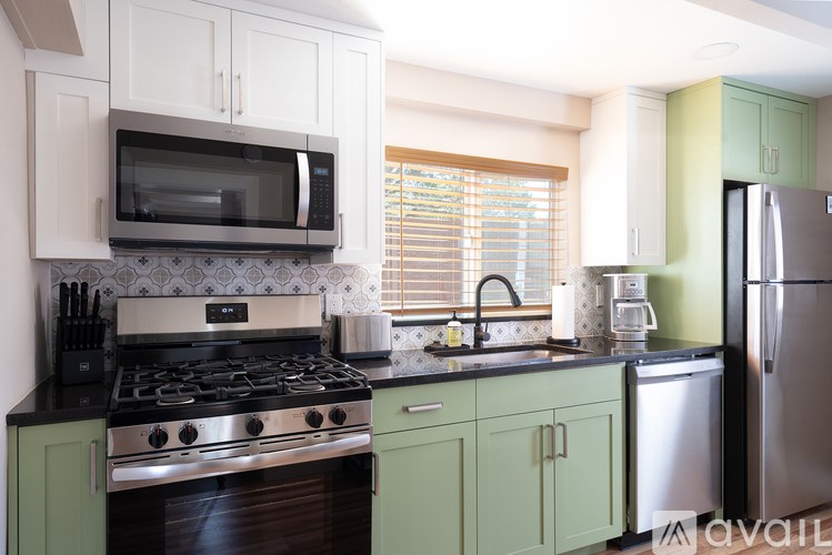 A kitchen with green cabinets and a stainless steel refrigerator.