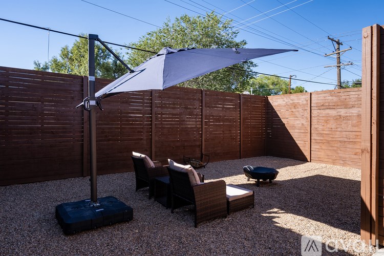 A patio with a table and chairs under a shade sail.
